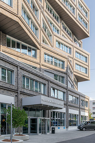 Entrance area of the Scandic Hotel with modern exterior façade and many windows in the mixed-use property die Macherei in Munich.