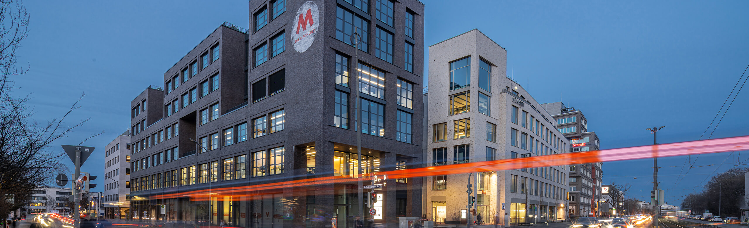 Exterior view of the mixed-use project die Macherei in Munich at night.